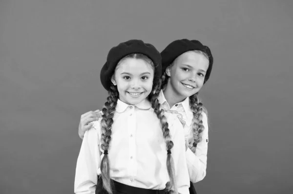 Amigos del colegio. Feliz niñas amigas en el fondo rosa. Adorables amigos disfrutando de la amistad. Pequeños amigos de la escuela sonriendo en uniforme y boinas con estilo — Foto de Stock