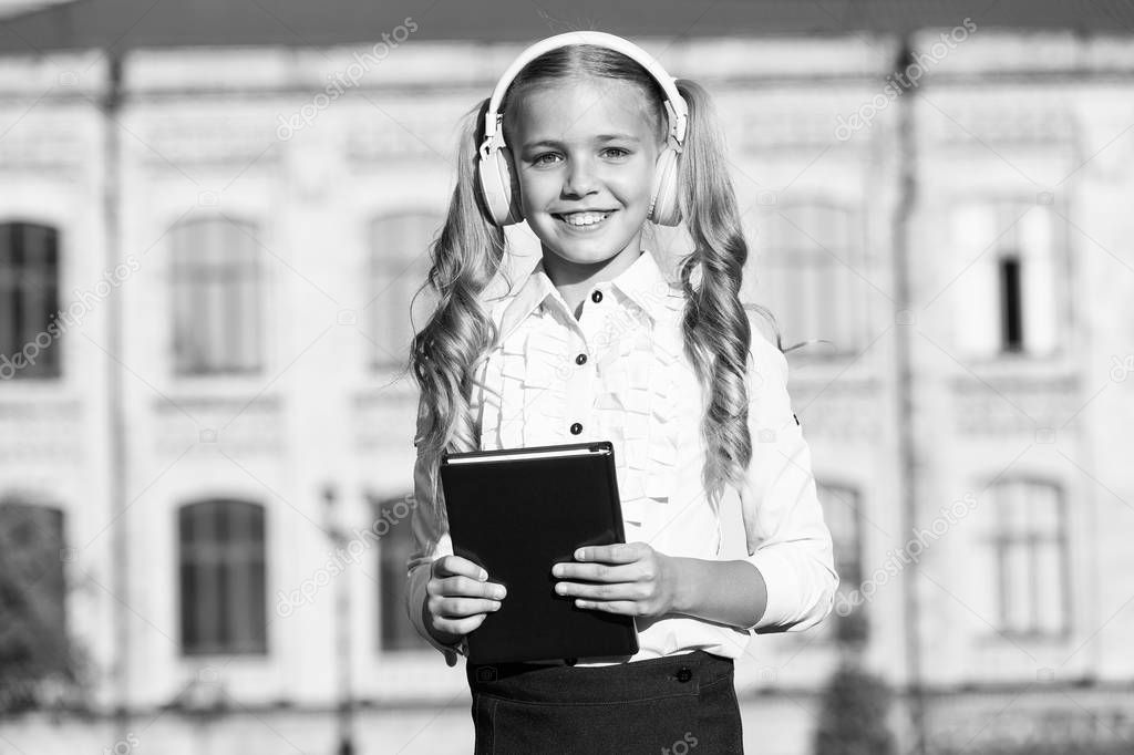 Listening school book. Digital technologies for learning. Elearning and modern methods. Girl cute schoolgirl hold book and headphones. Knowledge assimilate better this way. Audio book concept