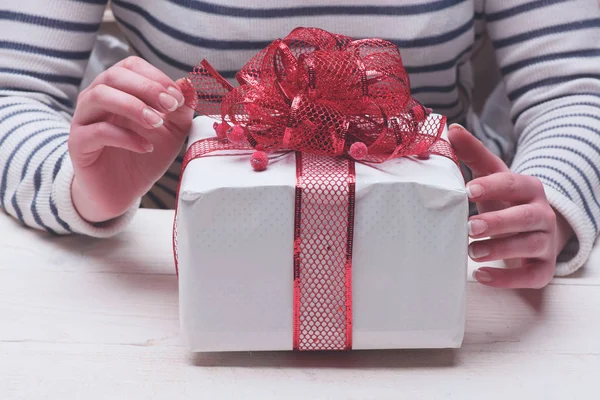 Female hands hold box wrapped in white paper with bow. — ストック写真