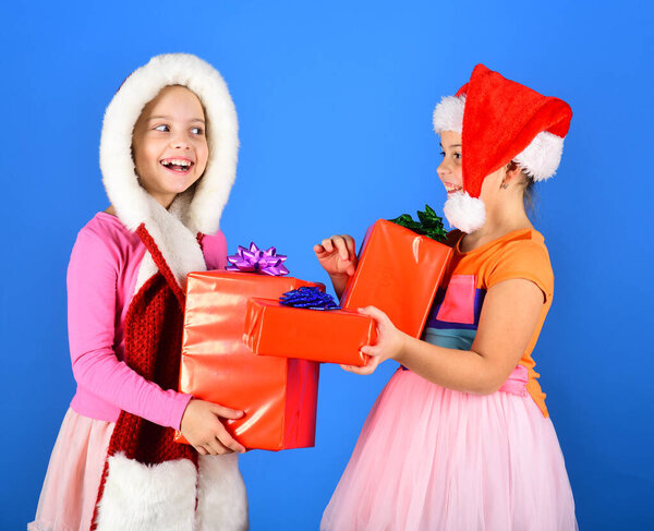 Girls open Christmas presents. Sisters in Santa Claus hats