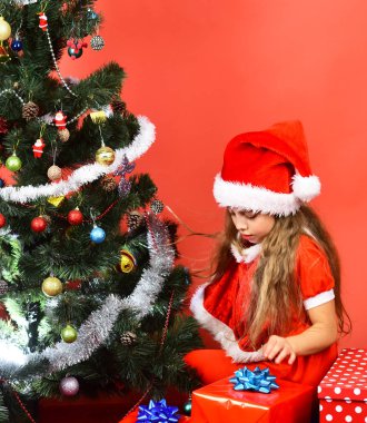 Noel şapkalı kız köknar ağacını süslüyor. Bayan Noel Baba