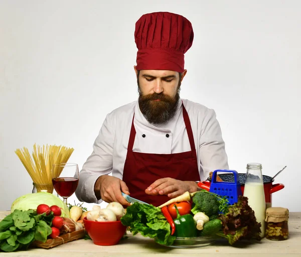 Cocinero con cara seria en uniforme se sienta junto a la mesa de la cocina — Foto de Stock