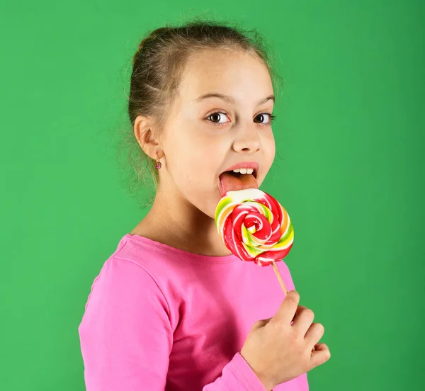 Concepto de tratamiento y dulces. Chica come caramelo dulce colorido grande . — Foto de Stock