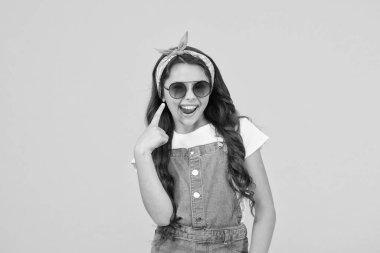 Şuna bir bak. Tatil modu başladı. Küçük moda düşkünü. Çocuk giyim mağazası. Retro kız. Yaz modası. Neşeli küçük kız sarı arka plan. Retro çocuk uzun saçı. Küçük çocuk klasik güneş gözlüğü.