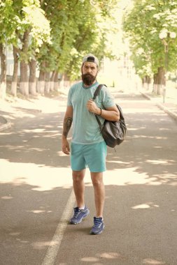 Yakışıklı atlet. Sırt çantası ile spor antrenörü egzersiz için açık havada hazır. Spor bir yaşam biçimidir. Parkta spor üniformalı adam yakışıklı sakallı yüz. Yaz egzersizi. Spor salonuna günlük yürüyüş. Sağlık