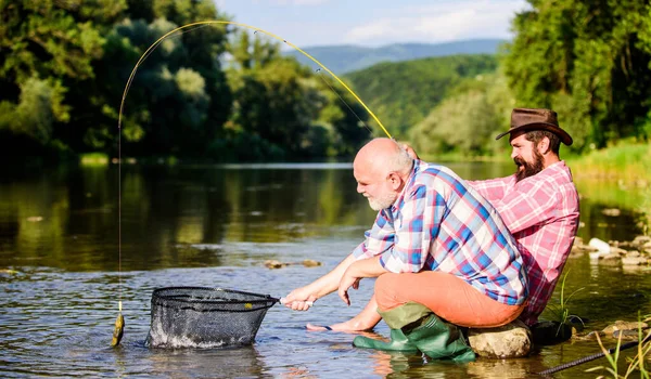 E 'andato a pesca. pesca d'altura. rilassarsi sulla natura. Due amici maschi che pescano insieme. hobby di pesce di mosca di uomini. pesca a riposo. Buona amicizia tra pescatori. padre in pensione e figlio barbuto maturo — Foto Stock