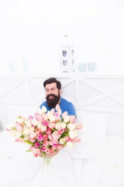 Homem barbudo feliz na cama. Buquê de presente de aniversário. Tulipa fresca de primavera. amor dia dos namorados. Dia das mulheres. tulipa flor para 8 de março. flores bom dia. humor positivo e felicidade — Fotografia de Stock