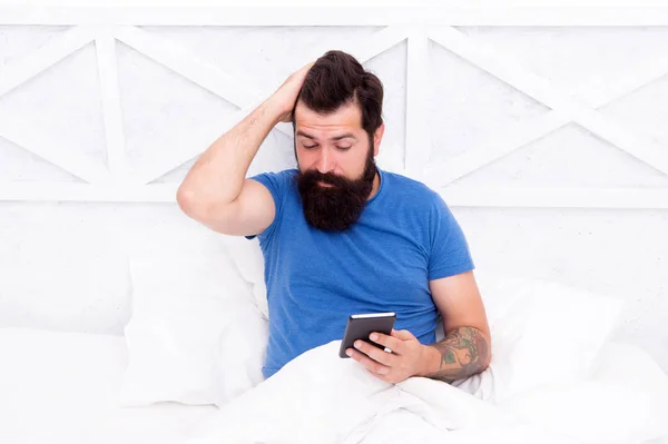 移动生活通过电话。 留胡子的男人在床上用手机。 希斯特在早上检查移动通知。 现代生活。 新技术。 家庭中的移动通信和技术 — 图库照片