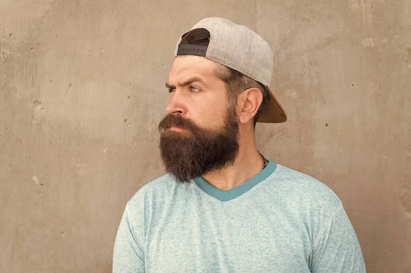 Poilu et barbu. Brutal hipster avec une moustache épaisse et des poils de barbe sur le visage non rasé. Hipster sur mur gris. Homme barbu dans le style branché hipster. Hipster caucasien portant une casquette de baseball occasionnelle — Photo