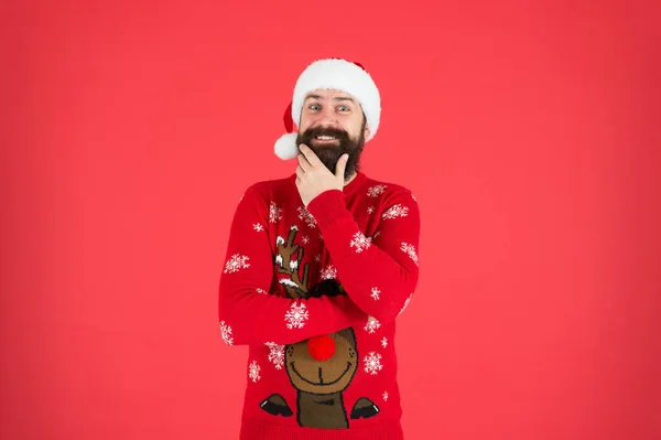 Alguma coisa na cabeça dele. Férias de inverno. Homem barbudo hipster usar chapéu de malha de inverno. Cabelo facial da barbearia. Moda de inverno. Um tipo a usar acessórios de roupa de Inverno. Barbudo Papai Noel fundo vermelho — Fotografia de Stock