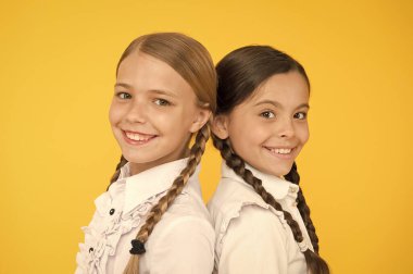 Zeki ve zeki. çocuk resmi moda. Yurtdışında eğitim. akıllı görünümlü çocuklar. okul arkadaşları. Üniformalı mutlu çocuklar. sarı arka planda küçük kızlar. dostluk ve kardeşlik. En iyi dostlar