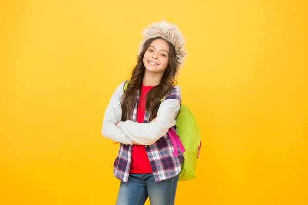 Έτοιμος για εξετάσεις. χειμερινά μαθήματα εκπαίδευσης. σχολική τσάντα κίτρινο φόντο. περίοδος επιλογής μαθημάτων. ανέμελος μαθητής παιδί. Το μικρό κορίτσι φοράει καπέλο από πτερύγιο. χειμερινό σχολείο και διακοπές — Φωτογραφία Αρχείου