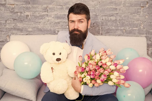 Man well groomed wear tuxedo bow tie hold flowers tulips bouquet and big teddy bear toy. Invite her dating. Romantic gift. Romantic man. Macho getting ready romantic date. Waiting for darling