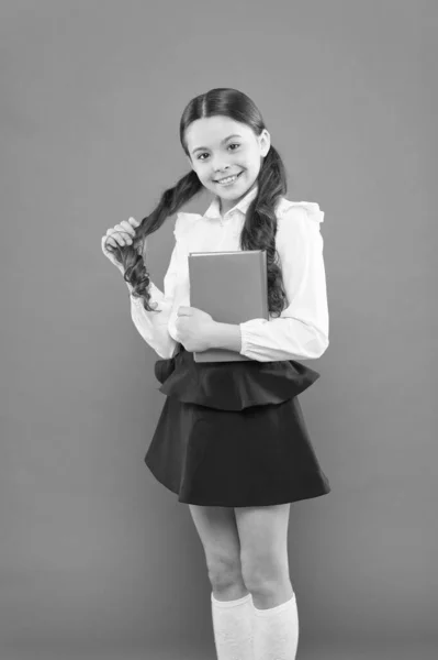 reading lesson. Book store concept. small girl in school uniform. get information form book. schoolgirl writing notes on orange background. back to school. happy child. Confident in her knowledge