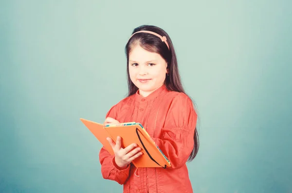 Lets look in the book of scientific knowledge. Cute little child writing knowledge test report. Adorable small girl holding book knowledge in hands. Knowledge day or September 1