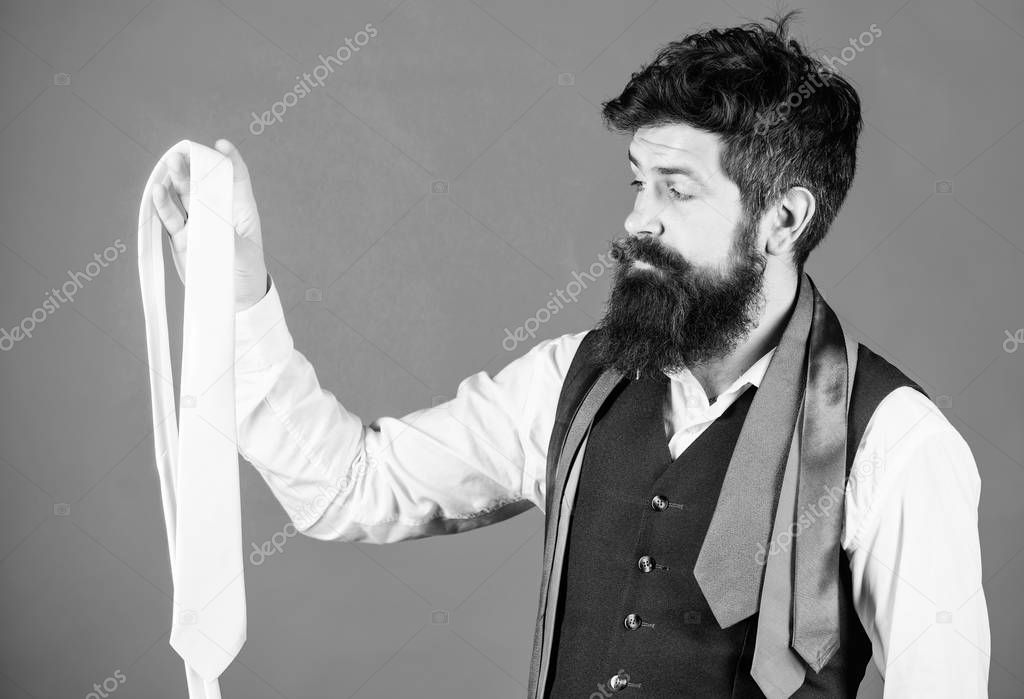A wonderful necktie to a classic look. Brutal caucasian hipster holding necktie. Bearded man with necktie collection. Businessman choosing necktie for business suit