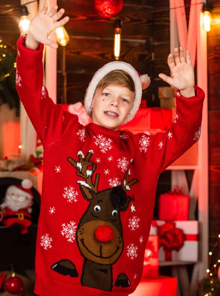 Щасливий підліток святкує новорічну вечірку. маленький хлопчик в червоному светрі для оленів. дитина в капелюсі Санта Клауса розважається вдома. веселого Різдва. він хоче подарувати Різдво. кращі зимові канікули — стокове фото