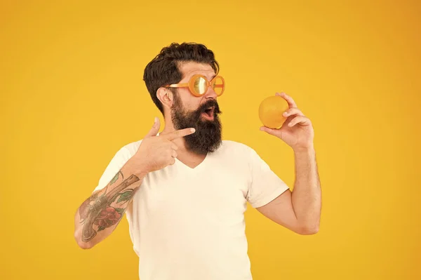 Цитрусова їжа. Хіпстер вказує пальцем на вітамінну їжу на жовтому тлі. Бородатий чоловік зі здоровою органічною їжею. Веганська їжа та дієта — стокове фото