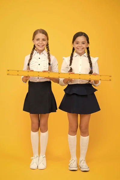 True friendship formula. school friendship. happy small girls study mathematics. students use yellow ruler. stem disciplines. back to school. Maths and geometry. Kids in uniform measuring — Stock Photo, Image