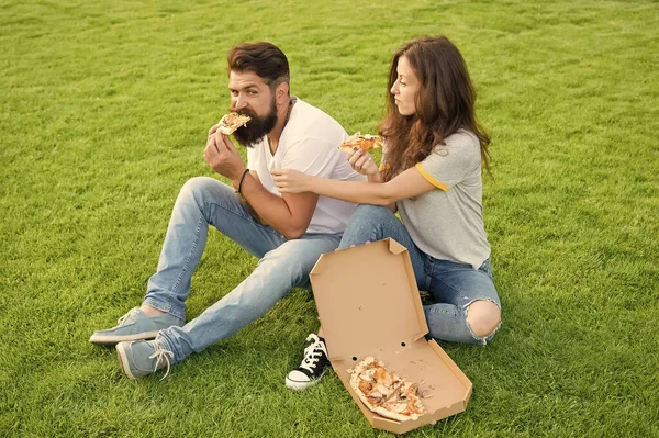 this is my slice. summer picnic on green grass. happy couple eating pizza. family weekend. couple in love dating. fast food. bearded man hipster and adorable girl eat pizza