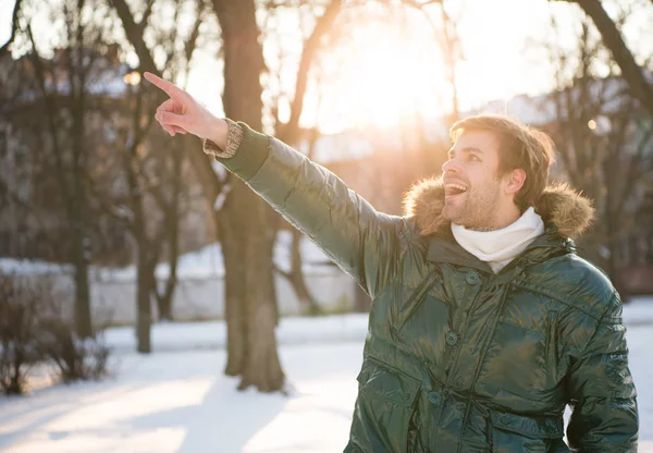 Happy guy green puffer coat. man enjoy winter landscape. nature is beautiful. look at that. man pointing finger. male in down coat with fur hood. feel warm and comfortable. favorite season — Stock Photo, Image