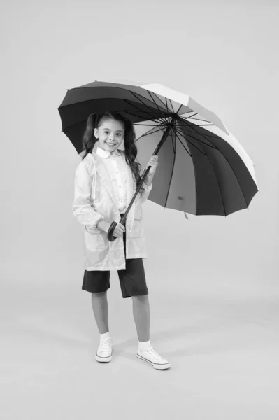 Despreocupado colegiala colorido paraguas usar impermeable impermeable. Lluvia de otoño. Ir a la escuela días lluviosos más divertido con accesorios brillantes. La lluvia no es tan mala si tienes ropa resistente al agua. — Foto de Stock