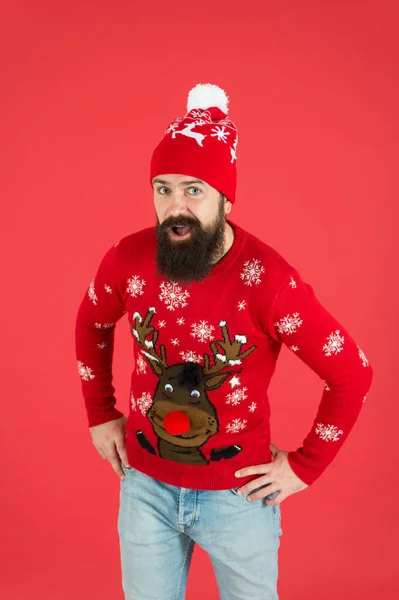 Happy new year concept. Join holiday party. Christmas eve. Winter outfit. Good vibes. Favorite winter season indoor activities. Hipster bearded man wear winter sweater and hat red background — Stock Photo, Image