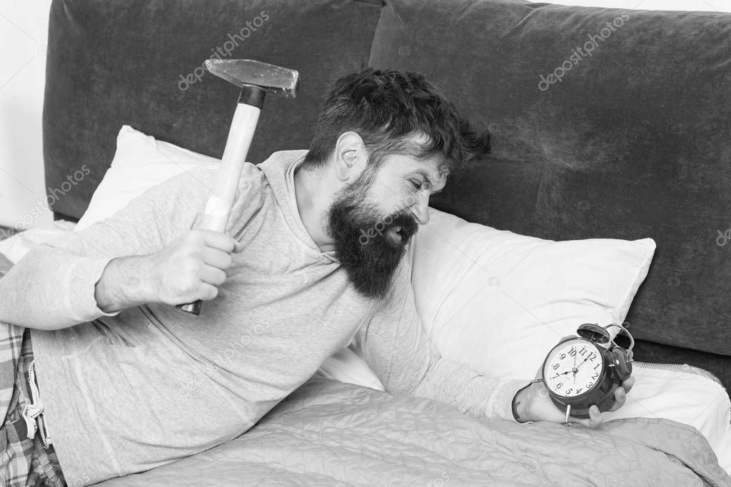 this is monday. hate noise of alarm clock. Irritated guy destroy annoying clock. Man awake unhappy with alarm clock ringing. Sleep longer. Healthy sleep concept. bearded man hipster want to sleep