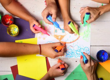 Eller renkli kalemleri tutar ve çocukların resimlerini çizer..