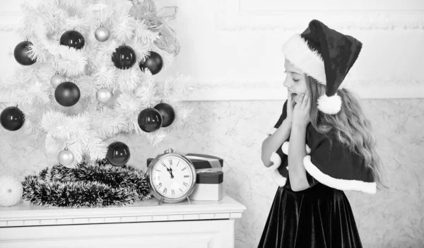 Compte à rebours du nouvel an. Les plans de la veille du Nouvel An de dernière minute qui sont en fait très amusants. Fille enfant santa chapeau costume avec horloge compte le temps de la nouvelle année. Combien de temps avant ? Dernière minute jusqu'à minuit — Photo