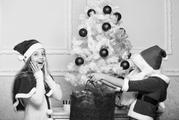 Santa bring some gifts. Unpacking christmas gifts. Merry christmas. Kids celebrate christmas with gifts. Boy kid dressed as santa with white artificial beard and red hat give gift box to girl — Stock Photo, Image