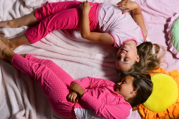 Girls lie on white and pink bed sheets bending — Stock Photo, Image