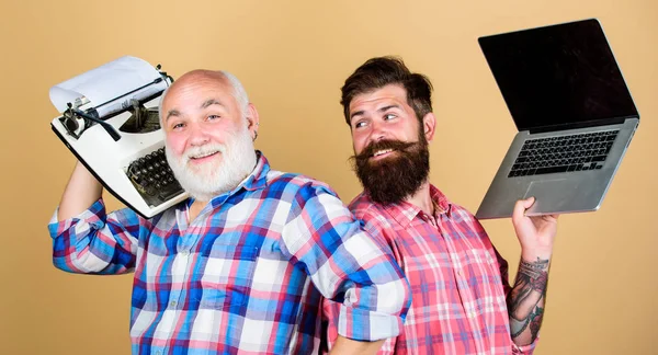若者と高齢者ビジネスアプローチだ父と息子よ技術開発と改善ですレトロタイプライター対ノートパソコンテクノロジー世代の戦いです現代の生活。髭の男2人ヴィンテージタイプライター — ストック写真