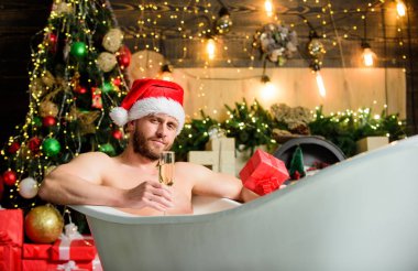 Kış tatili Yeni yıl. Küvette yatan olgun bir adam şampanya içer. Spa ve sağlık. Sıcak banyo. Sıcak banyo sağlık yararları. Noel Baba sıcak banyoda lüks içinde. Keyfini çıkar. Kendimi şımartıyorum.