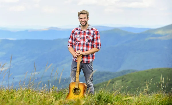 Músico hipster. Ambiente inspirador. Festival de música de verano al aire libre. Tocando música. Hombre músico con guitarra en la cima de la montaña. Músico inspirado. Silencio de montañas y sonido de cuerdas de guitarra — Foto de Stock