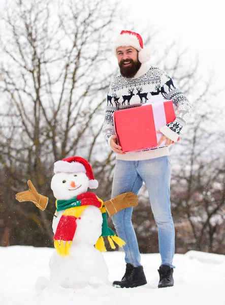 Fun and entertainment. Guy happy face snowy nature background. Winter games. Winter activity. Winter vacation. Man made snowman. Hipster with beard outdoors. Man with Santa hat having fun outdoors — Stock Photo, Image