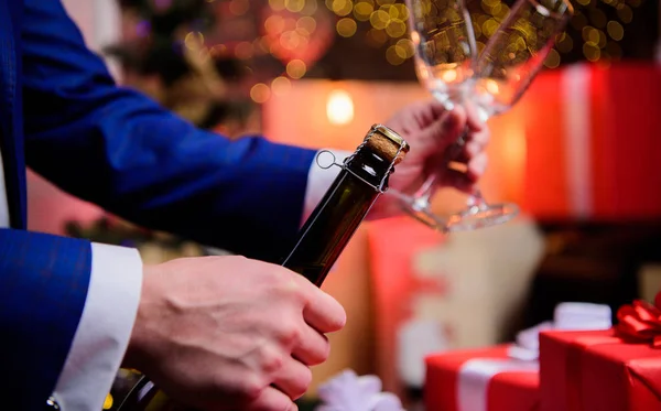 Celebre o Ano Novo com o champanhe. Brinde e aplaude conceito. Vamos comemorar. Mãos masculinas abrindo garrafa de champanhe derramando copos natal decorações fundo. Beba champanhe ou espumante — Fotografia de Stock