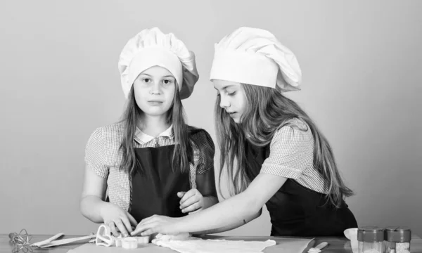 Cucinare biscotti allo zenzero. Ragazze sorelle divertirsi pasta allo zenzero. Bambini che cucinano biscotti insieme. Grembiuli per bambini e cuoco cappelli da cucina. Biscotti fatti in casa meglio. Ricetta di famiglia. Cucina abilità culinarie istruzione — Foto Stock