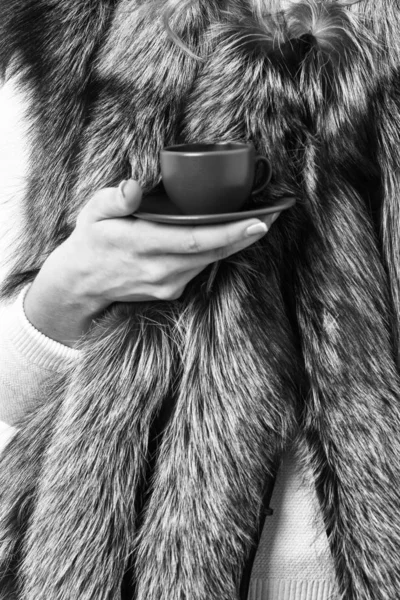 Элитный кофе. Женское пальто ручной мех держать коричневую чашку или кружку. Пейте кофе маленький керамический стаканчик закрыть. Насладитесь роскошным ароматом и горячим кофе. Потратьте несколько минут на кофе-брейк — стоковое фото