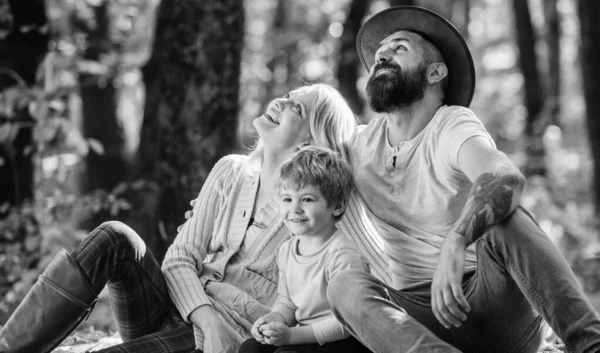 Concepto de día familiar. Familia feliz con niño niño relajándose mientras camina en el bosque. Fin de semana familiar. Madre padre e hijo pequeño se sientan de picnic en el bosque. Buen día para el picnic de primavera en la naturaleza. Unidos con la naturaleza — Foto de Stock