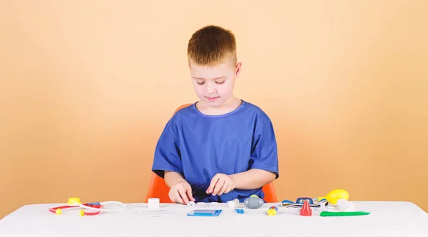 Educación médica. Juega a juego. Niño lindo niño futuro médico carrera. Vida sana. El niño pequeño médico se sienta en la mesa con estetoscopio y herramientas médicas. Concepto de medicina. Salud. Examen médico — Foto de Stock