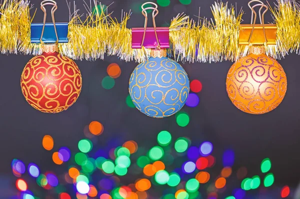 Concepto de adornos de Navidad. Bolas con adornos cuelgan de oropel brillante. Escoge una decoración colorida para el árbol de Navidad. Hojalata con adornos de Navidad fijados sobre fondo de luces de guirnalda desenfocadas — Foto de Stock