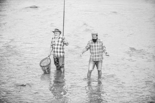 Pêcher ensemble. Les hommes sont dans l'eau. La pêche est bien plus que du poisson. Heureux pêcheur avec canne à pêche et filet. Loisirs et activités sportives. L'amitié masculine. Pêche père et fils. Week-end d'été — Photo