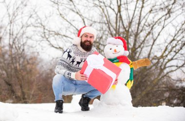 Sakallı adam kardan adam yapar. Mutlu yıllar. Noel Baba hediyesini dışarıda verir. Kış tatili Soğuk havada sıcak kazak. Mutlu hipster Noel 'e hazır. Kış mevsimi aktivitesi. Mutlu Noeller.