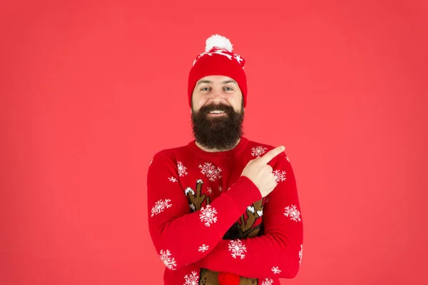 Camisola de rena homem barbudo maduro. hipster brutal em fundo vermelho chapéu de malha. Usa o clima de Natal. moda masculina de malhas. engraçado olhar homem apontando dedo. ainda acredito em santa claus — Fotografia de Stock