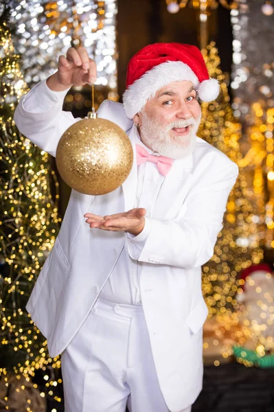 크리스마스 이브. 크리스마스 트리 축제 장식. 장식용 공 장난감 가게. 즐거운 마음으로 집을 단장하 십시오. 정원 채광 배경. 산타 모자를 쓴 수염있는 사업가. 하얀 턱시도를 쓴 노인 — 스톡 사진