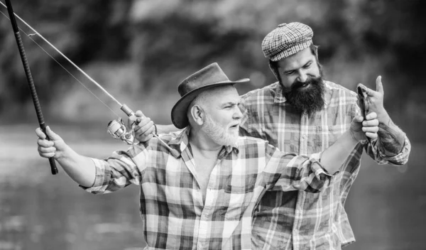 Concetto di fuga rurale. hobby. Tempo di pesca a mosca. Campeggio sulla riva del lago. turismo di caccia. padre e figlio pesca. due pescatori felici con canna da pesca e rete. Pesca d'altura. amicizia — Foto Stock