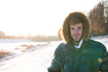 Kış için hazırlanıyorum. kopyalama alanı. Sıcak ve rahat hissediyorum. En sevdiğim sezon. Yeşil kabarık ceketli adam. Adam güneşli kış gününün tadını çıkarıyor. Erkek sezonluk moda. Soğuk algınlığı ve grip Kürk kapüşonlu erkek.