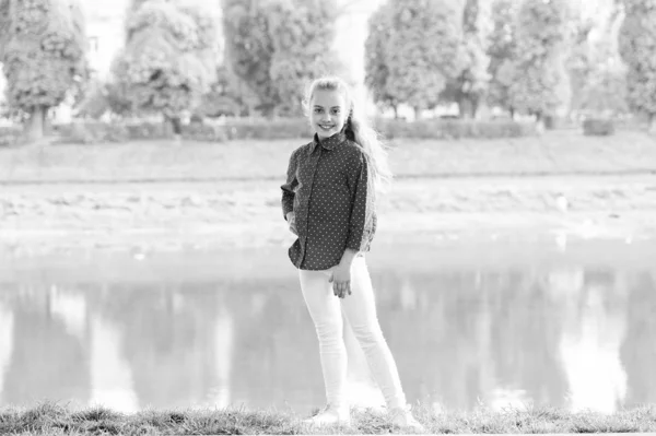 Una giornata tipica dell'infanzia. Ragazzina felice che indossa abiti casual per le vacanze a riva del fiume. Attività infantili nella giornata estiva. Buona infanzia. Infanzia e crescita — Foto Stock