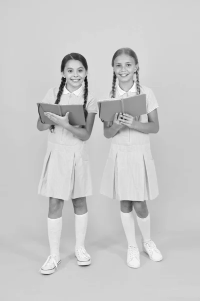 Letteratura per bambini. le ragazze piccole tengono la cartella di lavoro o il blocco note. enciclopedia libro per bambini. le bambine amano leggere. Alla vecchia maniera. amici felici in uniforme retrò. moda vintage per bambini. torna a scuola — Foto Stock